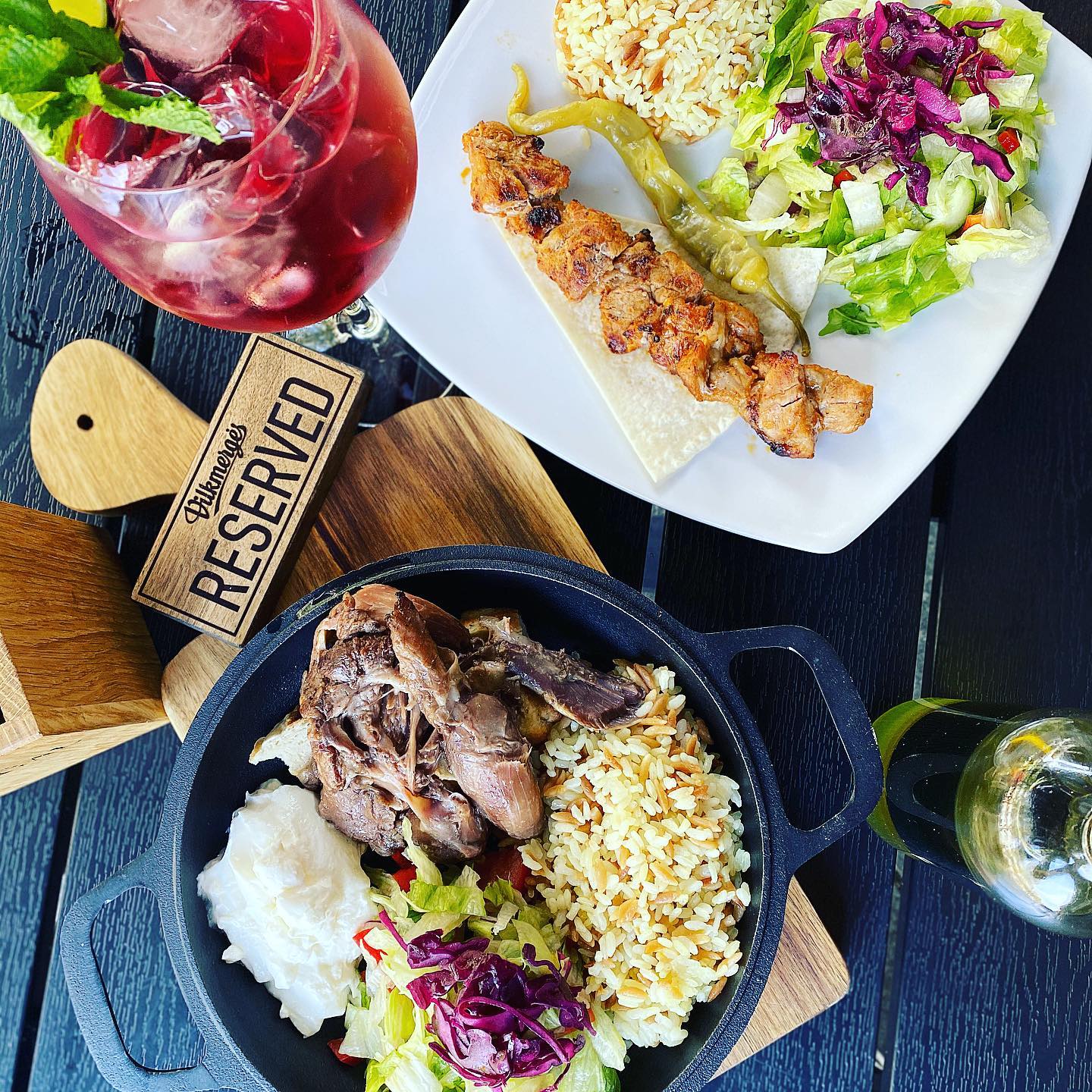 Sultinga grill mėsa su ryžiais, šviežiomis salotomis, šašlykas lėkštėje ir gaivus raudonos spalvos kokteilis „Mangal“ restorane.